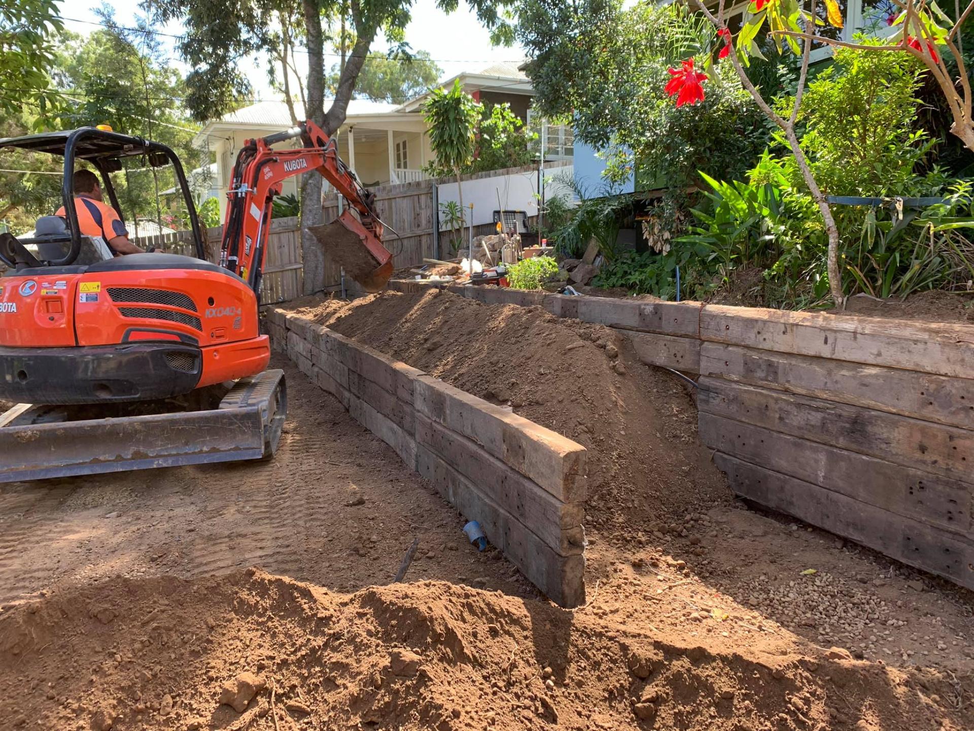 Sleeper retaining wall in progress — Kubota on site.
