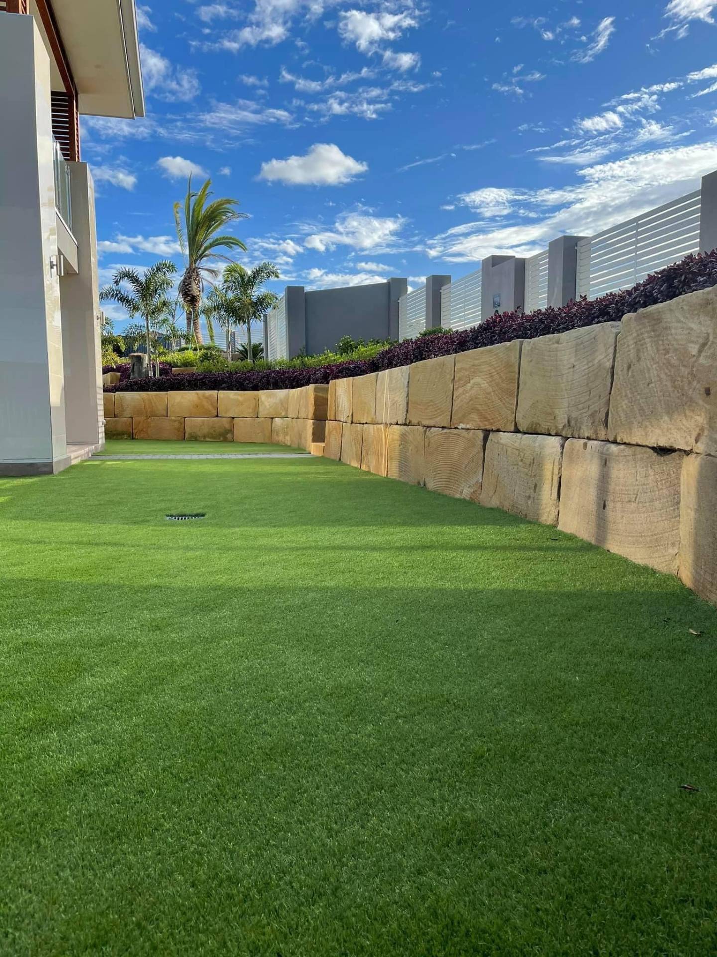 Sandstone block wall and fresh turf, finished.